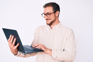 Young handsome man holding laptop looking positive and happy standing and smiling with a confident smile showing teeth