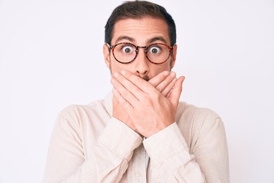 Young handsome man wearing casual clothes and glasses shocked covering mouth with hands for mistake. secret concept.