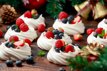 Meringue nests mini pavlova cakes with fresh berries strawberry blueberry raspberry and mint for dinner desert with Christmas festive decorations