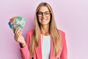 Young blonde woman wearing business style holding australian dollars looking positive and happy...