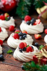 Meringue nests mini pavlova cakes with fresh berries strawberry blueberry raspberry and mint for dinner desert with Christmas festive decorations