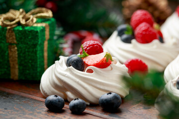 Meringue nests mini pavlova cakes with fresh berries strawberry blueberry raspberry and mint for dinner desert with Christmas festive decorations