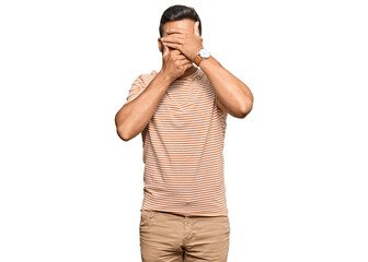 Naklejka premium Handsome hispanic man wearing casual clothes covering eyes and mouth with hands, surprised and shocked. hiding emotion
