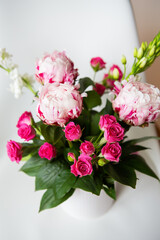 A beautiful bouquet of tender pink peonies and small roses stands on a white chair. Suitable for bridal bouquet, birthday. Close-up, top view.