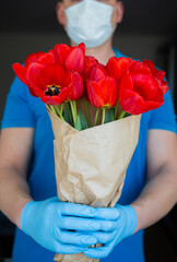 Contactless delivery of a bouquet of beautiful red tulips