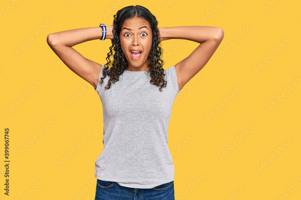 Poster Young african american girl wearing casual clothes crazy and scared with hands on head, afraid and surprised of shock with open mouth