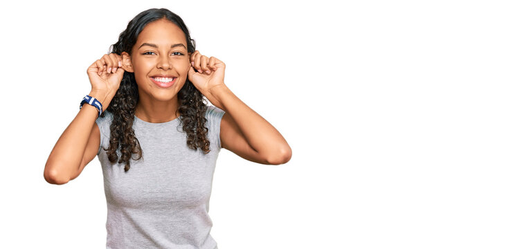 Young african american girl wearing casual clothes smiling pulling ears with fingers, funny gesture. audition problem