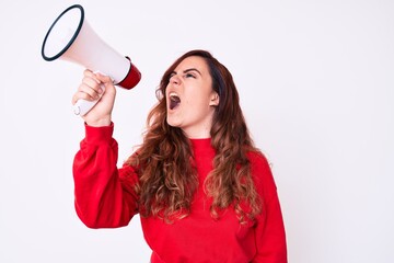 Young beautiful brunette woman screaming using megaphone over isolated white background