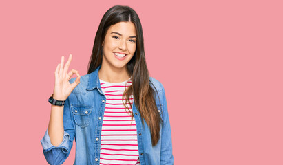 Young brunette woman wearing casual clothes smiling positive doing ok sign with hand and fingers. successful expression.
