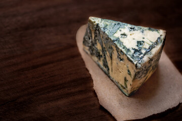 Blue cheese Gorgonzola on a dark wooden background. Mold cheese with copyspace. Fresh  typical italian blue cheese close up.