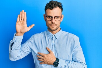 Young hispanic man wearing casual clothes and glasses swearing with hand on chest and open palm,...