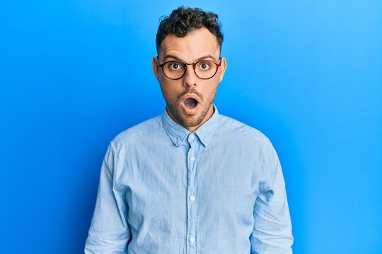 Young hispanic man wearing casual clothes and glasses afraid and shocked with surprise and amazed expression, fear and excited face.