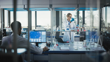 Fototapeta premium Female Medical Scientist Wearing White Coat and Safety Glasses uses Micropipette while Examining Testing Sample. Innovative, Experimental Drugs Research, Biotech Development in High-Tech Laboratory