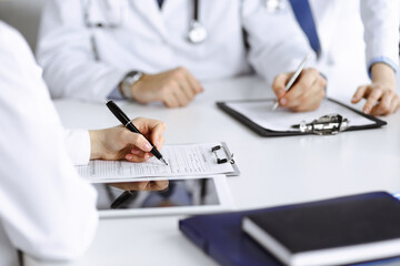 Group of unknown doctors are sitting at the desk and discussing problems or disease treatment in modern hospital office. Coronavirus countering, patient help in medicine concept