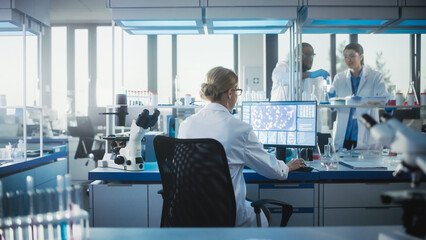 Medical Laboratory with Team of Scientists Working. Microbiologist is Using Personal Computer,...