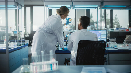 In Medical Laboratory: Chief Microbiologist Shows Petri Dish with Tissue Sample to a Colleague,...