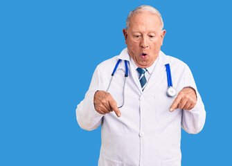 Senior handsome grey-haired man wearing doctor coat and stethoscope pointing down with fingers showing advertisement, surprised face and open mouth