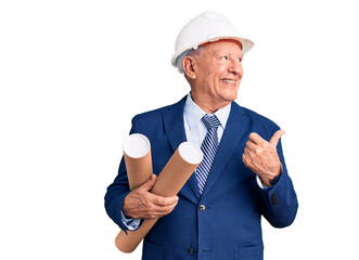 Senior handsome grey-haired man wearing architect hardhat holding blueprints pointing thumb up to the side smiling happy with open mouth