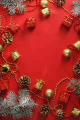 Christmas decorations with spruce branches on a red background with free space.