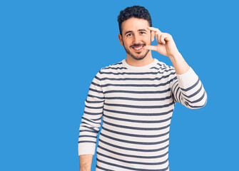 Fototapeta premium Young hispanic man wearing casual clothes smiling and confident gesturing with hand doing small size sign with fingers looking and the camera. measure concept.