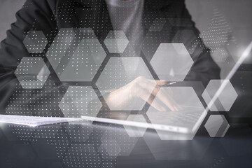 Businesswoman typing on laptop in office. Abstract technology hologram. Double exposure.