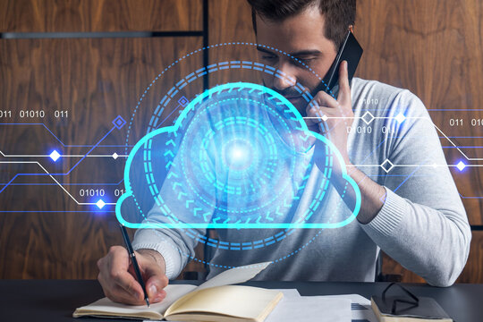 Handsome man in casual long sleeve talking phone and taking notes at office workplace. Double exposure. IT storage cloud hologram as a concept of information security.