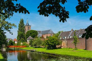 Fototapeta na wymiar canal, bridge, city wall, trees and church Grote Kerk in fortified city Vianen. The Netherlands