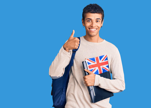 Young african amercian man wearing student backpack holding binder and uk flag smiling happy and positive, thumb up doing excellent and approval sign