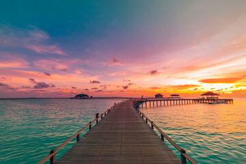 Sunset on Maldives island, luxury water villas resort and wooden pier. Beautiful sky and clouds and...