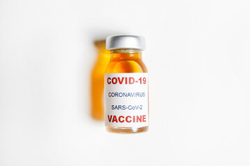 Macro shot of antiviral vaccine vial for immunization against covid-19 virus. Isolated on white background with copy space for text. Close up, top view.