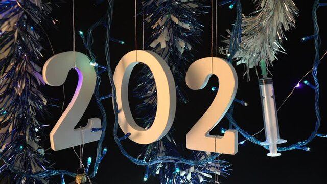 2021 With A Syringe Hanging With Garlands And Christmas Lights - Coronavirus New Year Concept - close up