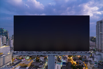 Blank black road billboard with Bangkok cityscape background at night time. Street advertising poster, mock up, 3D rendering. Front view. The concept of marketing communication to sell idea.