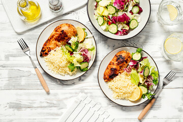 Grilled chicken breast, fillet garnished with couscous and fresh vegetable salad of lettuce, arugula, spinach and cucumber . Healthy lunch menu. Diet food. Top view.