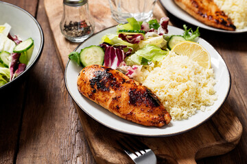 Grilled chicken breast, fillet garnished with couscous and fresh vegetable salad of lettuce, arugula, spinach and cucumber . Healthy lunch menu. Diet food. 