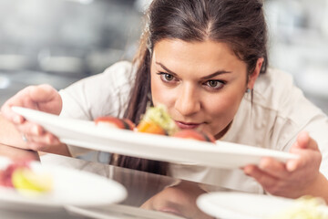 Equal opportunity for women in professional gastronomy with female chef plating up a meal