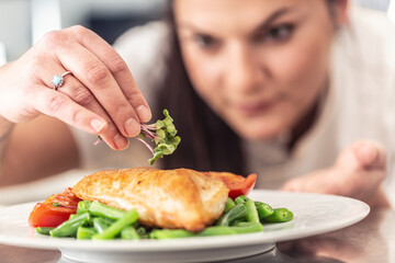 Steamed veg and healthy chicken breasts plated by a female chef