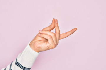 Hand of caucasian young man showing fingers over isolated pink background snapping fingers for success, easy and click symbol gesture with hand