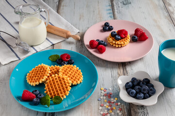 blueberries, raspberries and waffles on a rustic white wooden background