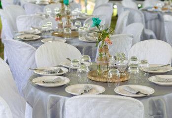 circular tables to celebrate wedding lunch with white dishes, glasses, fork, knifes and flowers