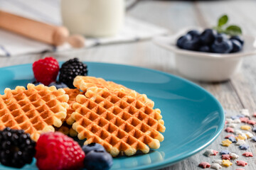 blueberries, raspberries and waffles on a rustic white wooden background