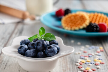 blueberries, raspberries and waffles on a rustic white wooden background