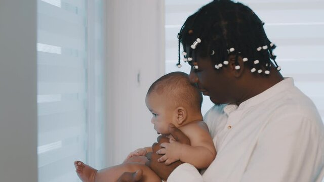 African american black father holding his mulatto baby near the window. High quality 4k footage