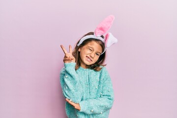 Little beautiful girl wearing cute easter bunny ears smiling with happy face winking at the camera...