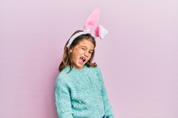Little beautiful girl wearing cute easter bunny ears winking looking at the camera with sexy...