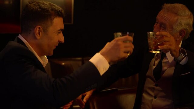 Cheers . senior executive business man and customer toasting with whiskey and handshake on bar counter at nightclub or pub . old man drinking alcohol in meeting after work to deal business Agreement