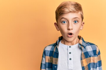 Little caucasian boy kid wearing casual clothes scared and amazed with open mouth for surprise,...