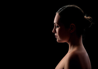 Fototapeta premium young girl posing in backlight on a black background