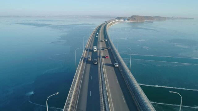 Aerial drone view of low-water bridge across the bay with moving car. Active movement of transport cars vehicles in different directions.
