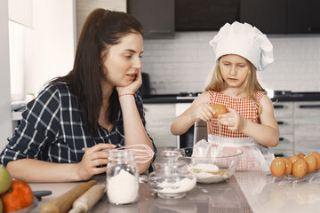 Family in a kitchen. Beautiful mother with little daughter. Woman in a black shirt.