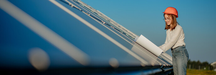 Handsome Architect Woman Examining a Draft Map or Blueprint Project Plan, Worker Activity Looking Out in Photovoltaic Cell Farm or Solar Panels Field